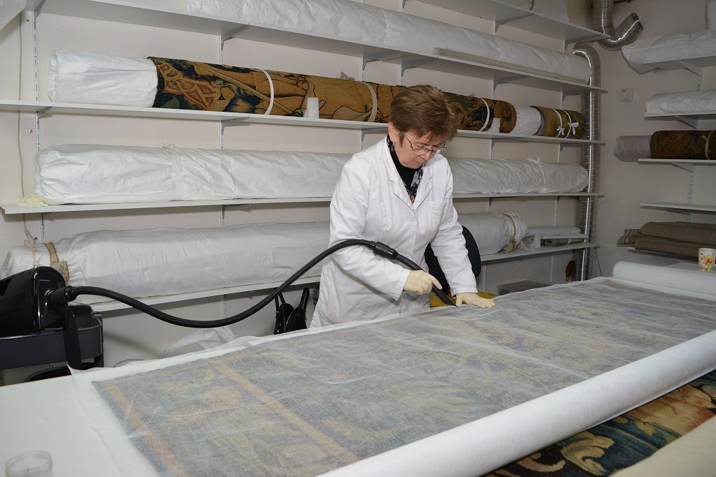 Restauratrice aspirant une tapisserie sous tulle