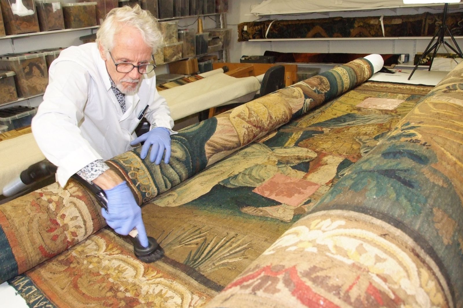 Jean-Marie Dor dépoussiérant une tapisserie ancienne à l’atelier